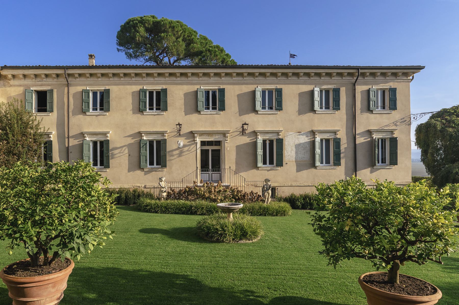 Facciata della villa vista dal giardino, con statue e siepi ordinate